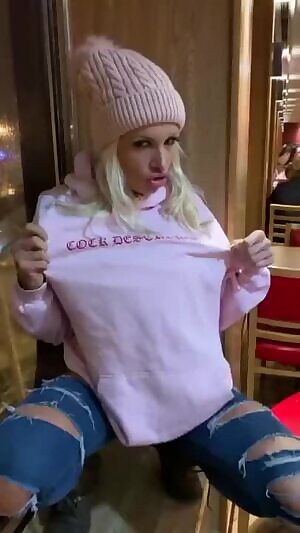 Crazy slut flashing big fake tits in a restaurant and masturbating her pussy through a hole in her pants